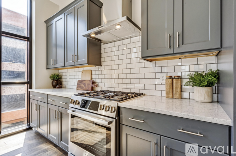 A kitchen with a stove top and a white tiled backsplash.