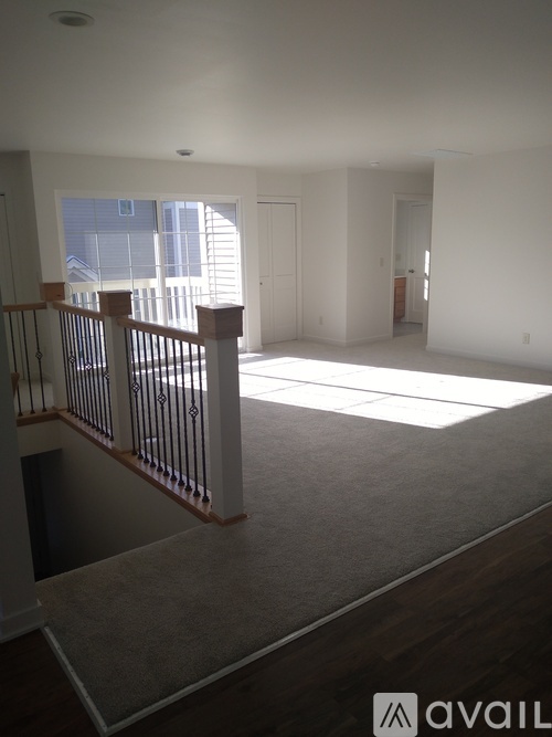 A spacious living room with a carpeted floor and a staircase leading to the upper level.