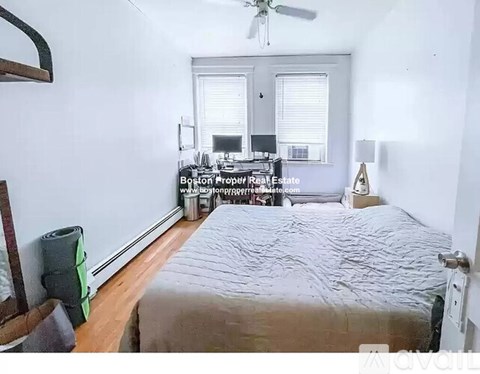 A bedroom with a bed, a window with blinds, a ceiling fan, and a wall hanging.