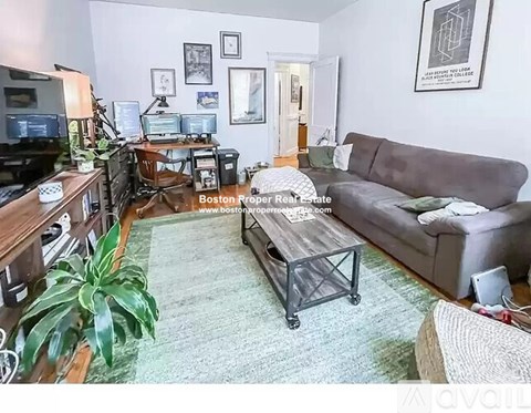 A living room with a grey couch and a green rug.