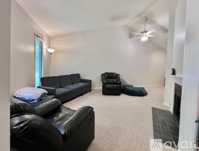A living room with a black leather couch and a black recliner.