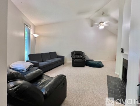 A living room with a black leather couch and a black recliner.
