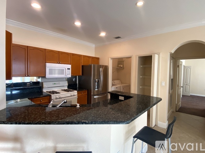 A kitchen with a black counter top and a white fridge.