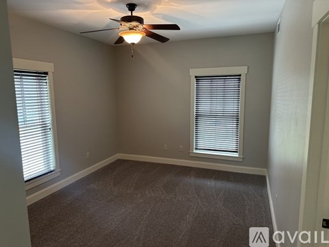 A room with a ceiling fan and a window with blinds.