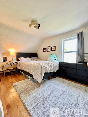 A bedroom with a bed, nightstand, and window.