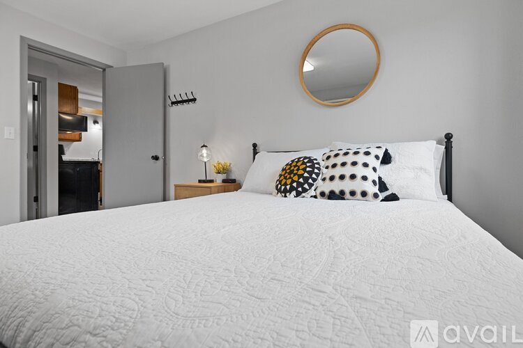 A bedroom with a large bed and a round mirror on the wall.