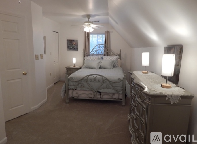 A bedroom with a bed, nightstand, and a window with curtains.