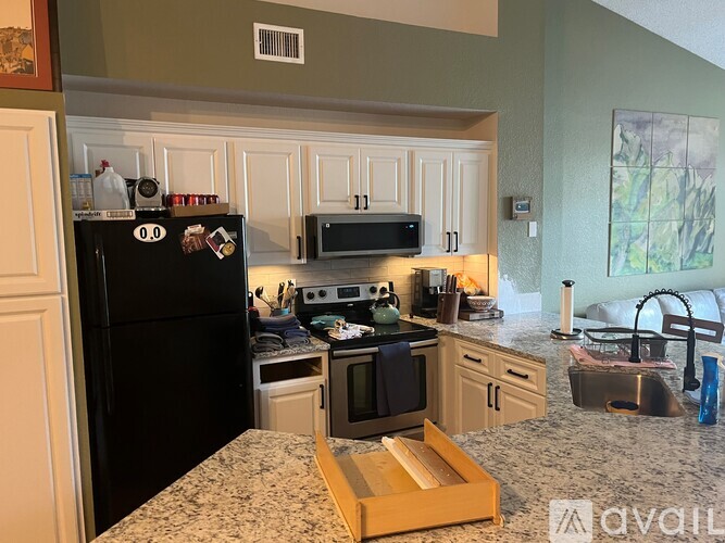 A kitchen with a black refrigerator and white cabinets.