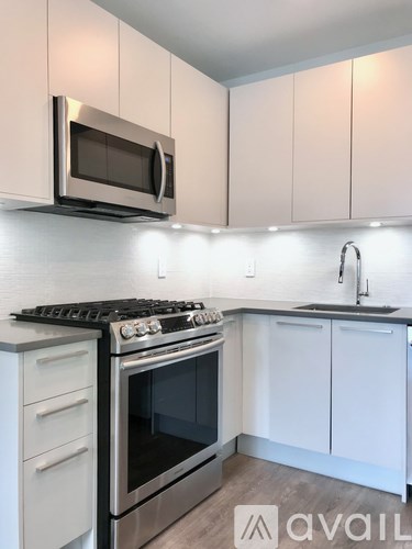 A kitchen with white cabinets and a stainless steel oven and microwave.
