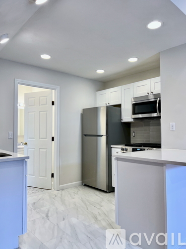 A kitchen with a white door and a stainless steel refrigerator.