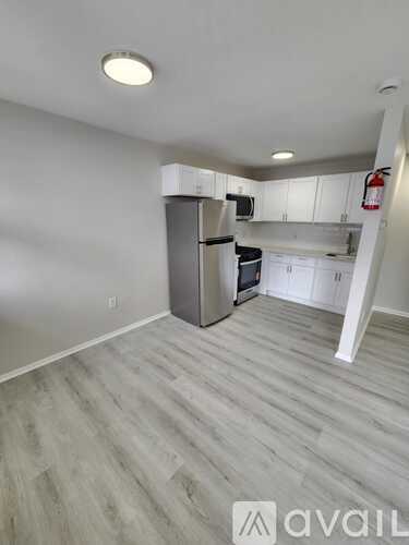 A kitchen with white cabinets and a grey fridge.