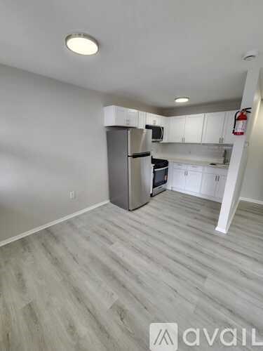 A kitchen with white cabinets and a grey fridge.