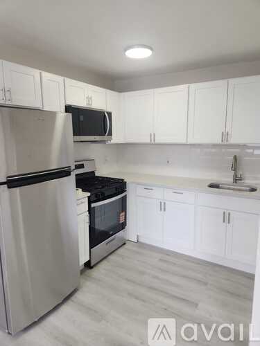 A kitchen with white cabinets and a stainless steel refrigerator.
