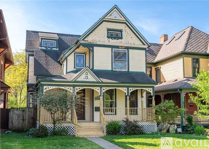 A Victorian style house with a front porch and a tree in front.