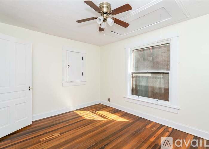 A room with a ceiling fan and a window with a view of a building outside.