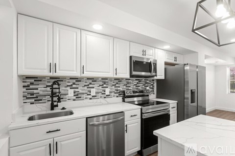 A kitchen with white cabinets and a marble countertop.