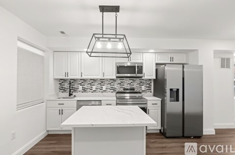 A modern kitchen with a white island and stainless steel appliances.