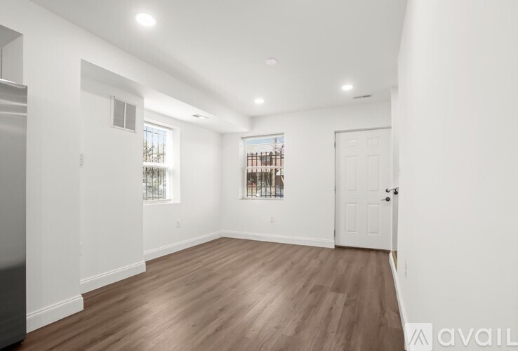 A spacious room with wooden flooring and white walls.