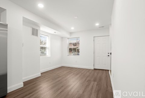 A spacious room with wooden flooring and white walls.