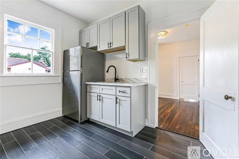 A kitchen with white cabinets and a stainless steel refrigerator.