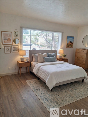 A bedroom with a large bed, a nightstand with a lamp, and a dresser.