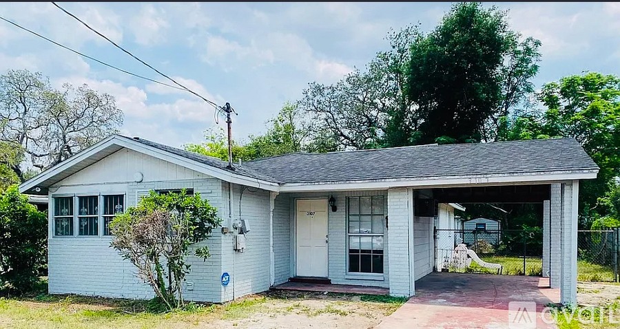 A small white house with a covered porch and a blue sign on the front door.
