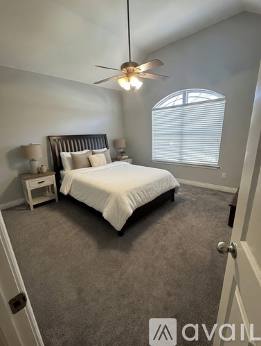 A bedroom with a bed, nightstands, and a ceiling fan.