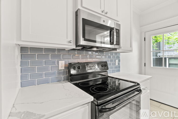 A kitchen with a black stove top oven and a microwave above it.
