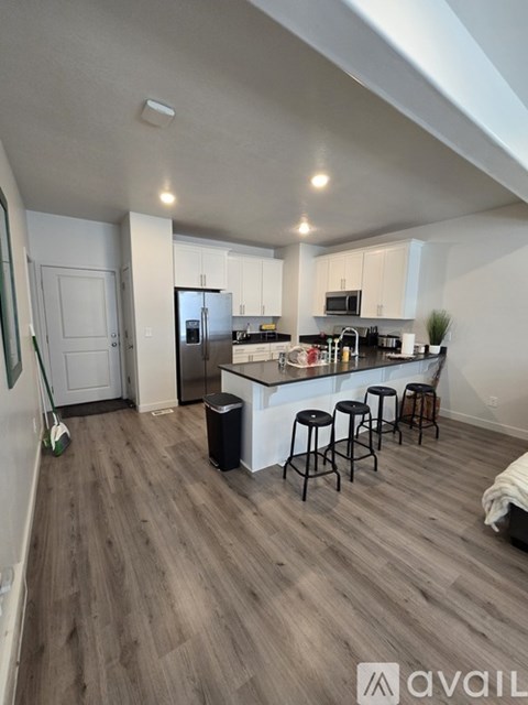 A kitchen with a bar stool and a fridge.