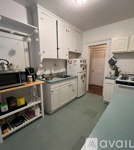 A kitchen with white cabinets and a white fridge.