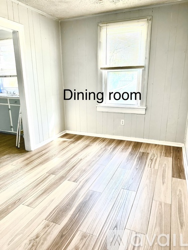 A dining room with a wooden floor and a window.