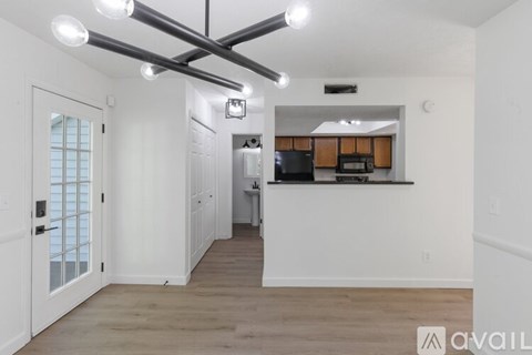 A modern kitchen with white cabinets and a wooden floor.