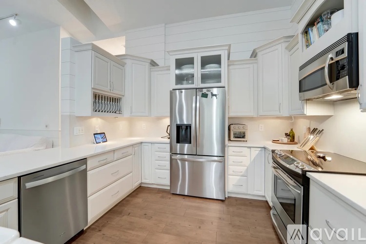 A kitchen with white cabinets and a stainless steel refrigerator.