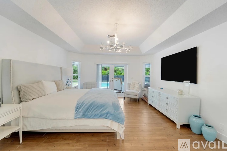 A bedroom with a large bed and a television on the wall.