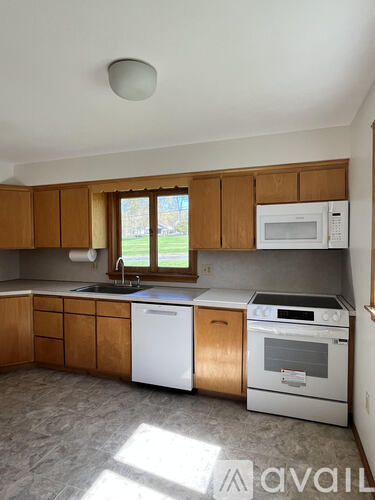 A kitchen with wooden cabinets and a white dishwasher.
