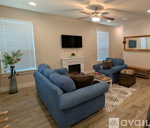 A living room with a blue couch, a fireplace, and a television mounted on the wall.