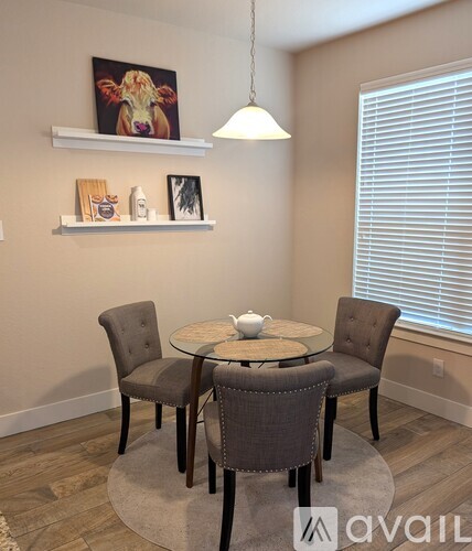 A dining room with a table set for two and a painting of a cow on the wall.