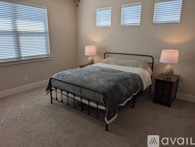 A bedroom with a bed, two lamps, and a nightstand.
