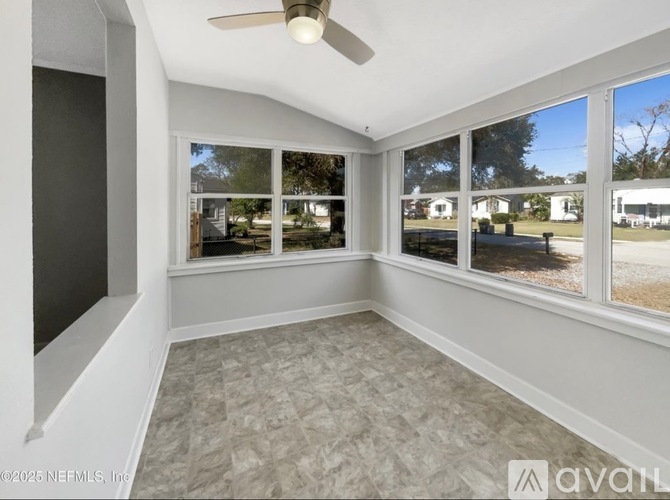 A sunny room with a ceiling fan and large windows.