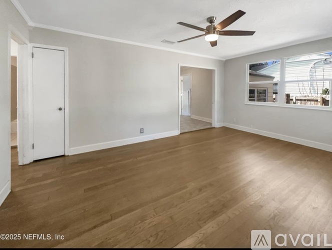 A spacious room with wooden flooring and a ceiling fan.