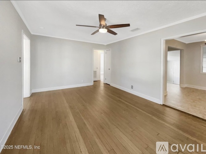 A spacious room with wooden flooring and a ceiling fan.