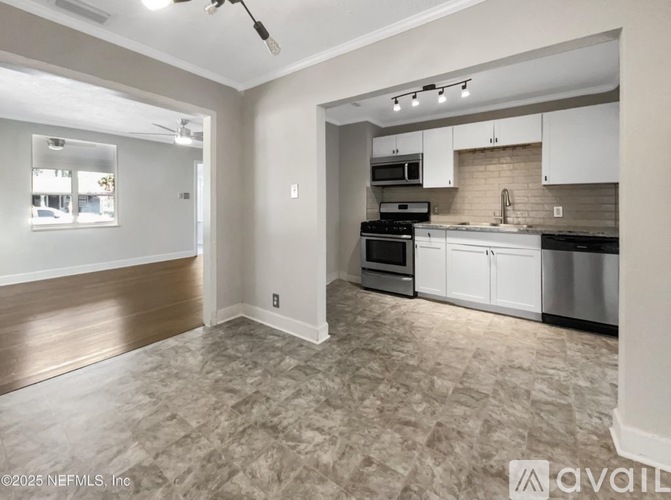 A well-lit kitchen with white cabinets and a tiled floor.