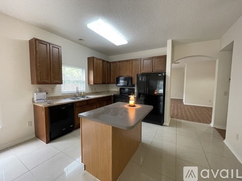 A kitchen with a black refrigerator and wooden cabinets.