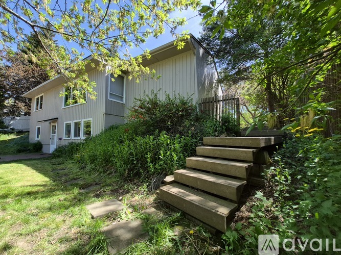 A house with a white exterior and a wooden staircase in front of it.