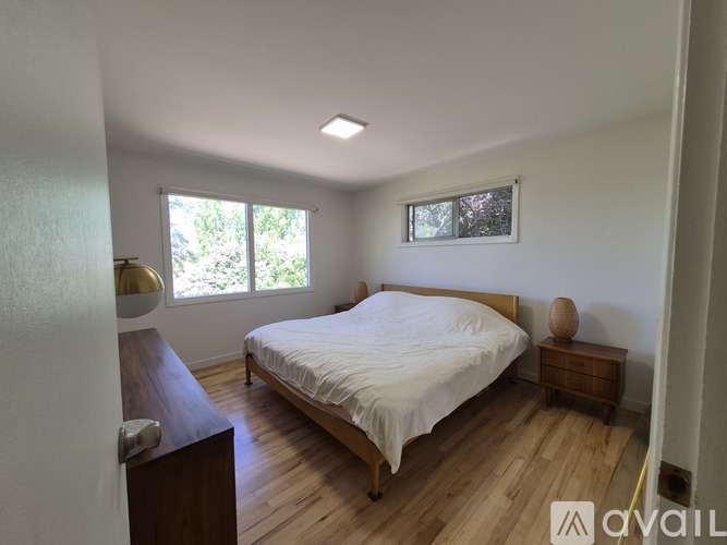 A bedroom with a bed, nightstand, and window.