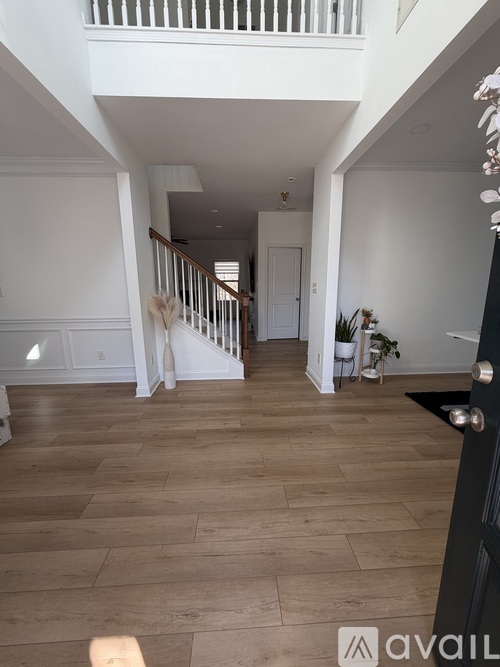 A spacious living room with wooden flooring and white walls.