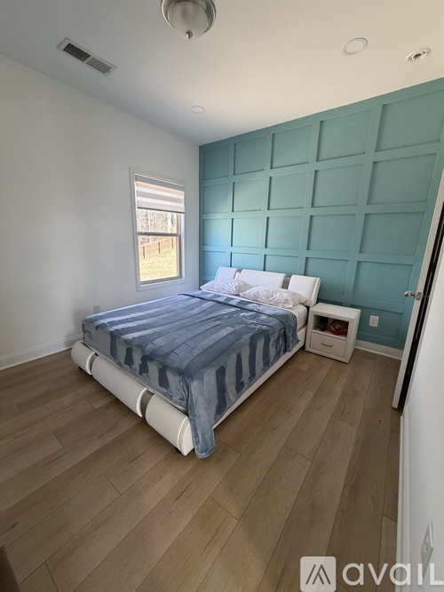 A bedroom with a bed, nightstand, and window.