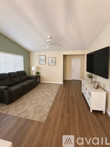 A living room with a black sofa and a television on the wall.