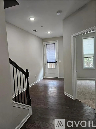 A hallway with a black railing and wooden floors.