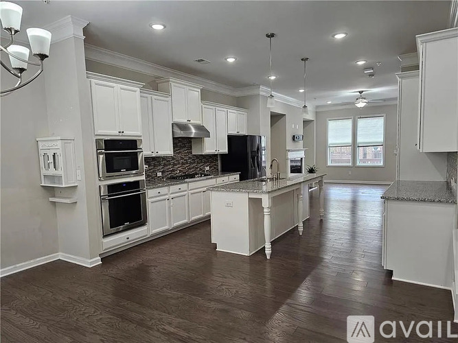 A spacious kitchen with white cabinets and a dark countertop.